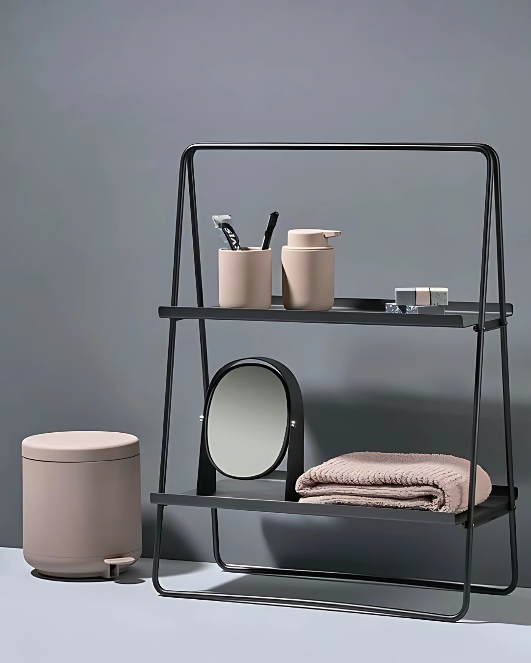 A minimalist Black A-Table leans against a white wall, showcasing its simple and elegant design. The table features two rectangular shelves supported by an A-shaped frame made of slender, rounded metal. Its open structure and clean lines create a light and airy feel.