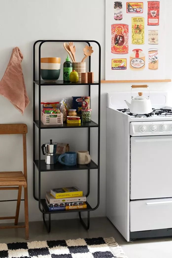 Black metal Alana narrow storage shelf with four shelves, displaying kitchenware and cookbooks. Modern industrial shelving unit for kitchen organization in Lebanon.