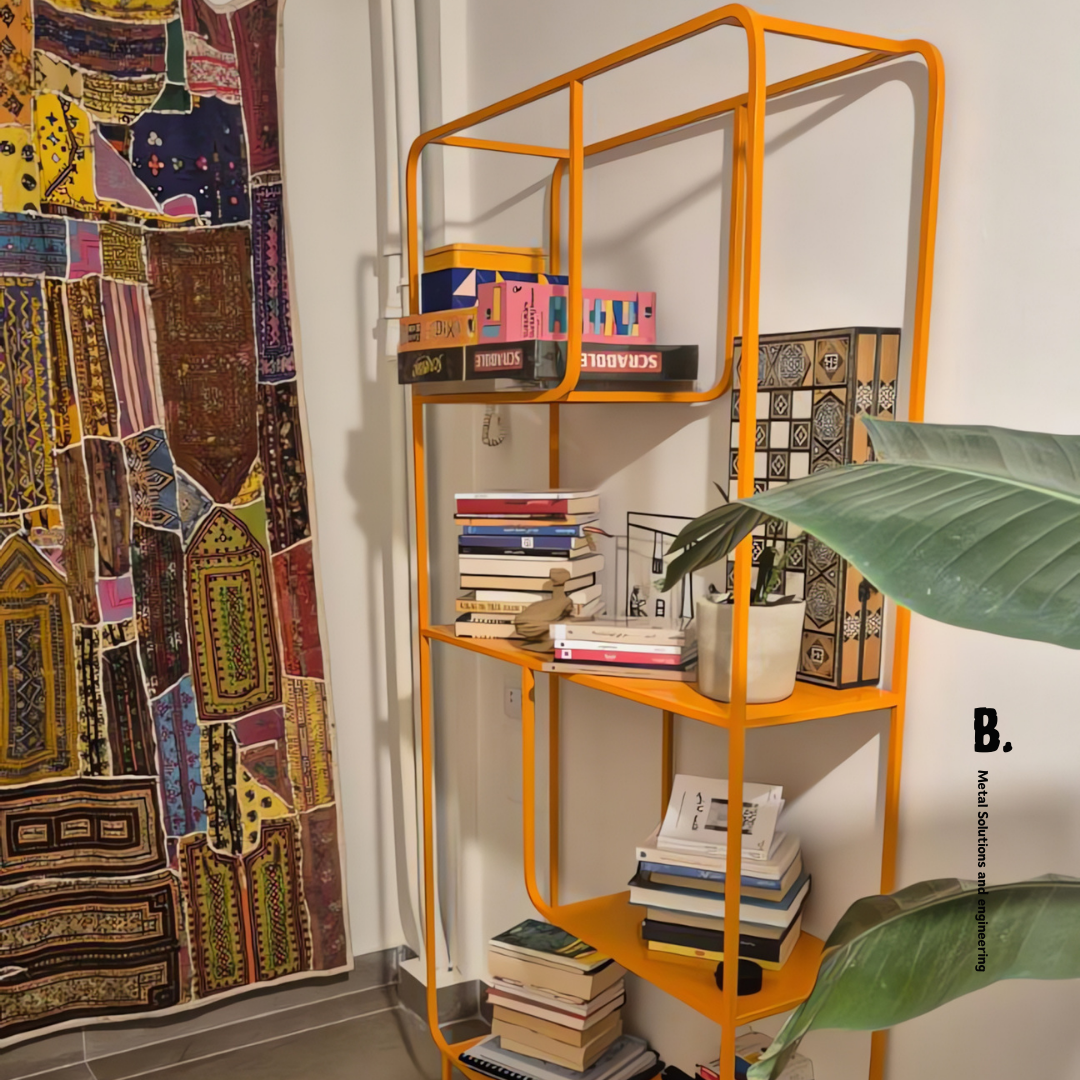 Orange metal Alana bookshelf from Urban Outfitters, displaying books, vases, and a speaker. Modern open shelving unit for home decor and storage in Lebanon.
