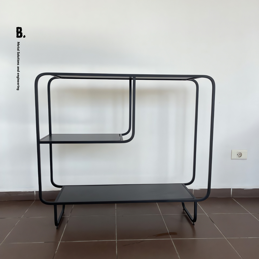 The Alana console, a black metal table with shelves, showing a vase, books, and a speaker.