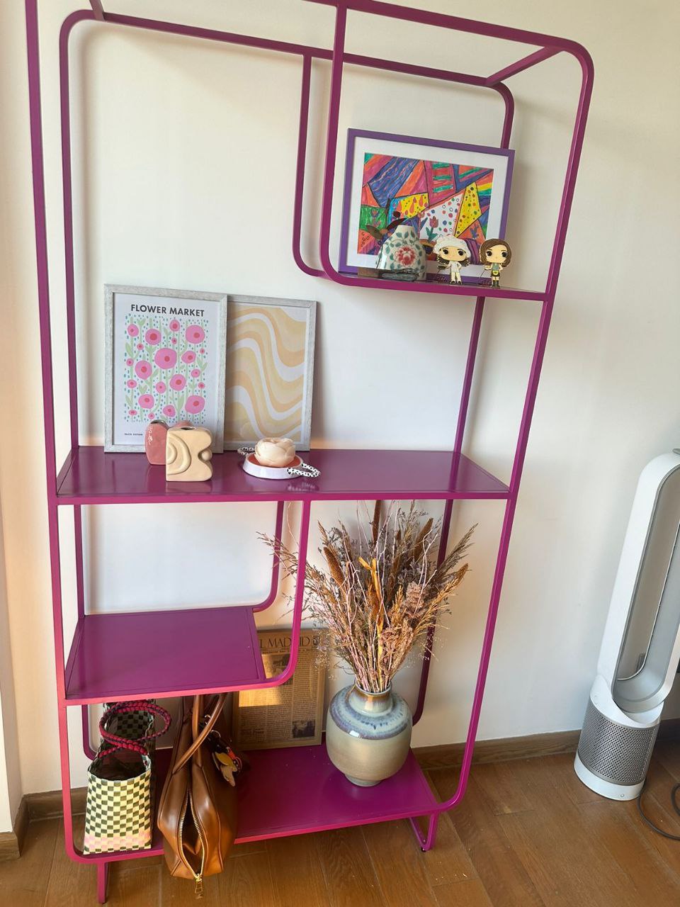 Pink metal Alana bookshelf from Urban Outfitters, displaying books, vases, and a speaker. Modern open shelving unit for home decor and storage in Lebanon.