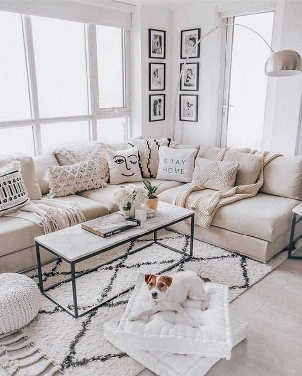 A rectangular coffee table with a white marble top and a black metal frame, situated in a bright living room.