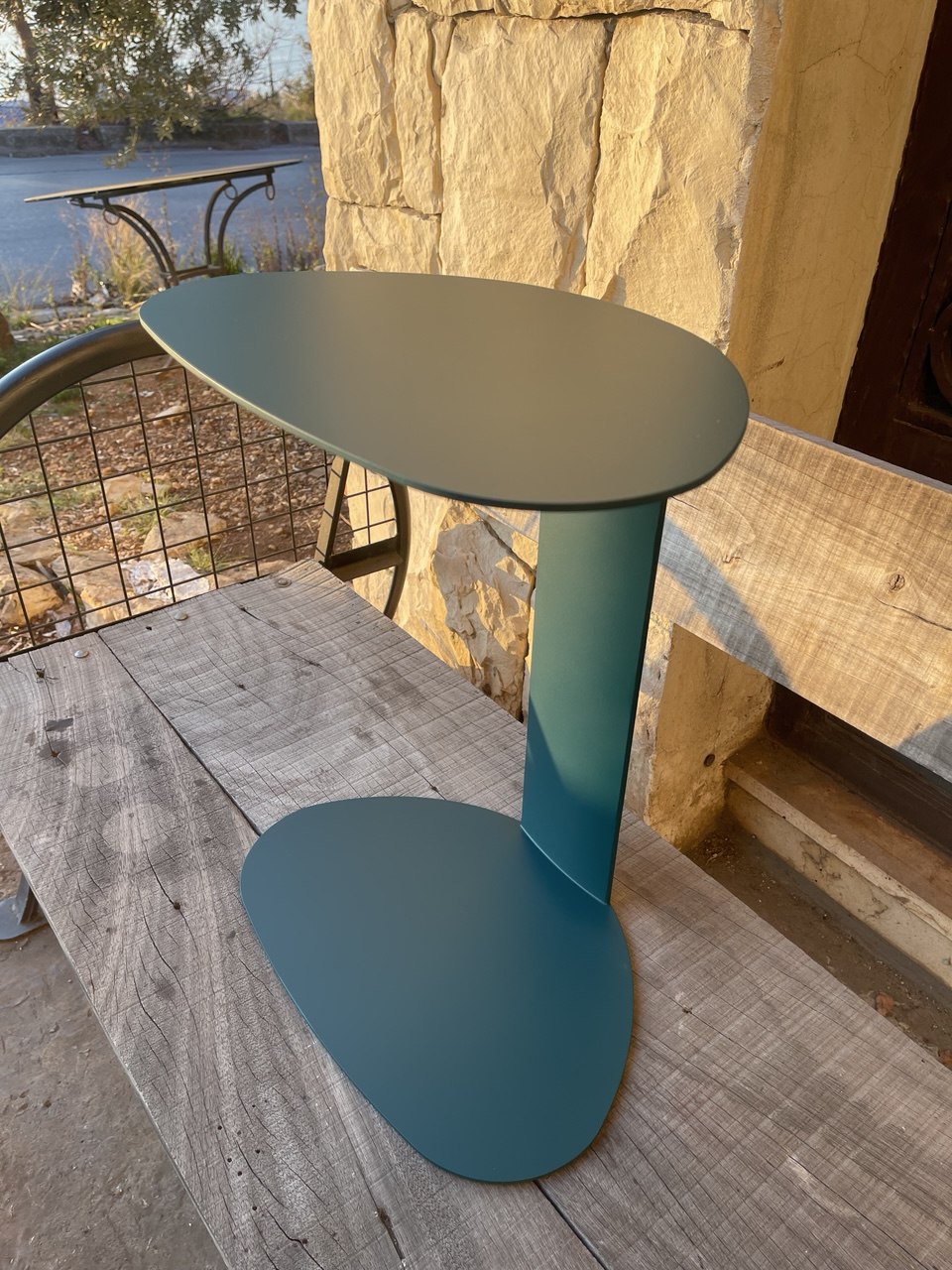 Green side table with a slim, space-saving design and unique top shape.