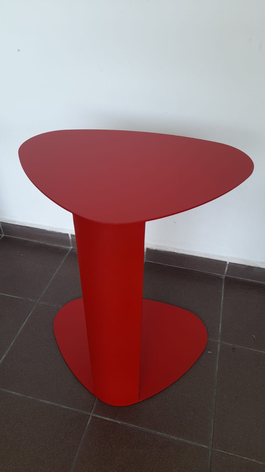 Red side table with a slim, space-saving design and unique top shape.