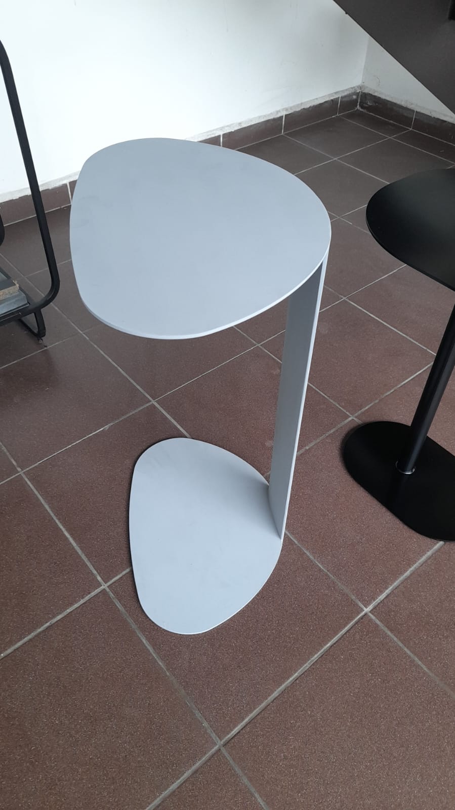 White side table with a slim, space-saving design and unique top shape.