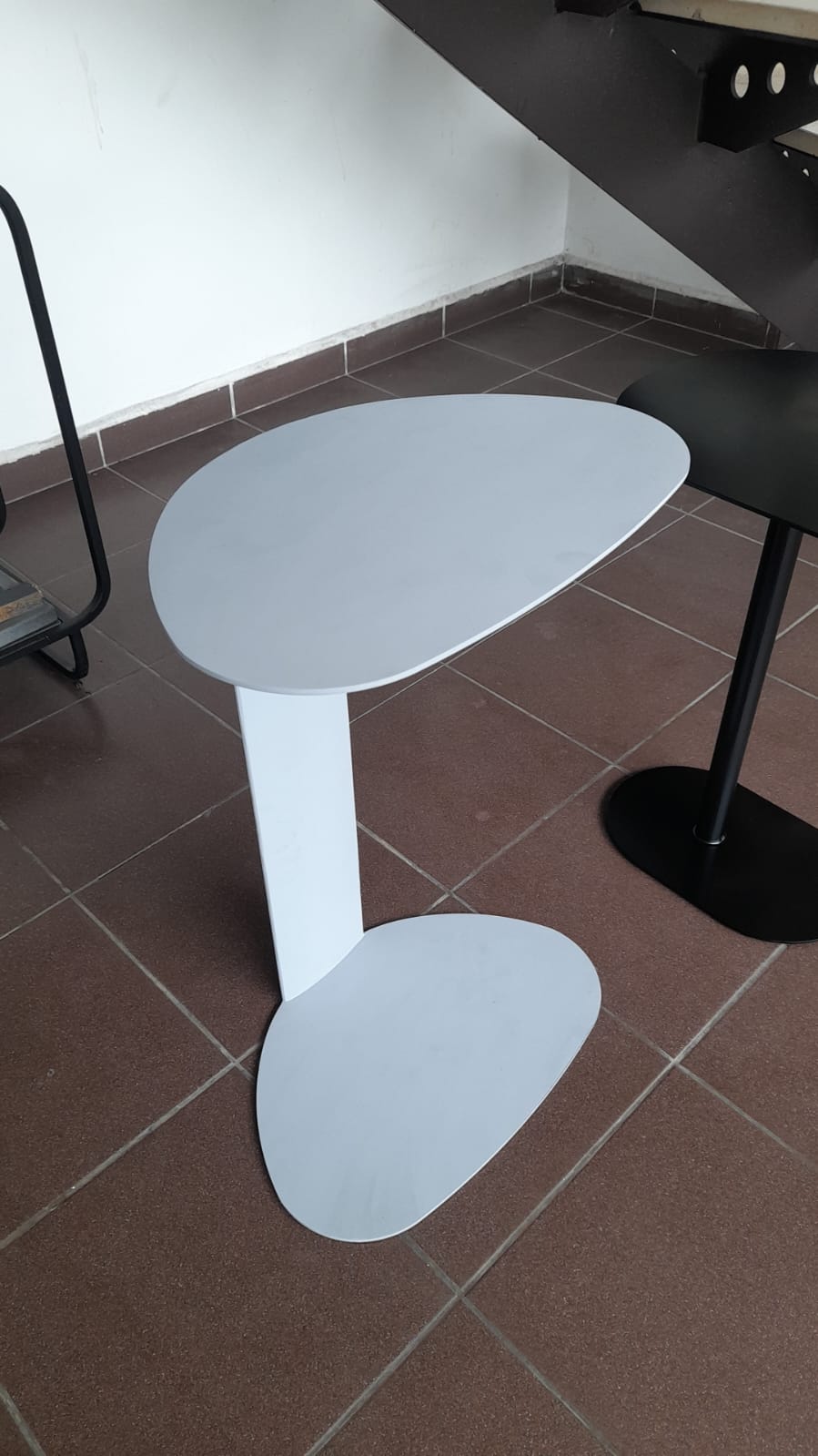White side table with a slim, space-saving design and unique top shape.