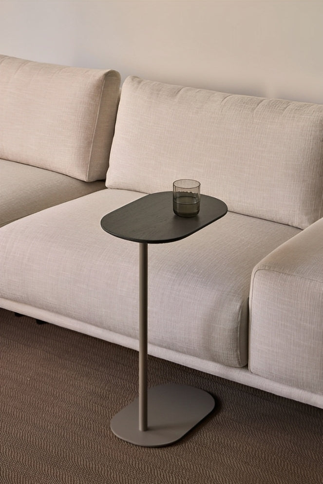 Contemporary black C-shaped side table with an oval top, positioned over a sofa.
