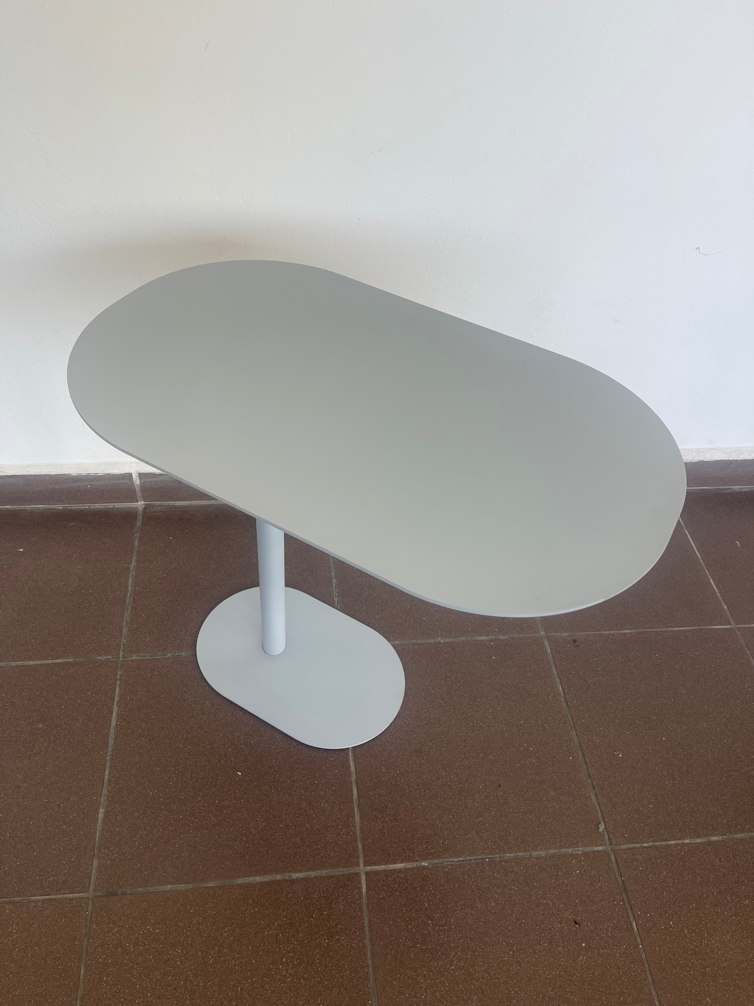Contemporary black C-shaped side table with an oval top, positioned over a sofa.