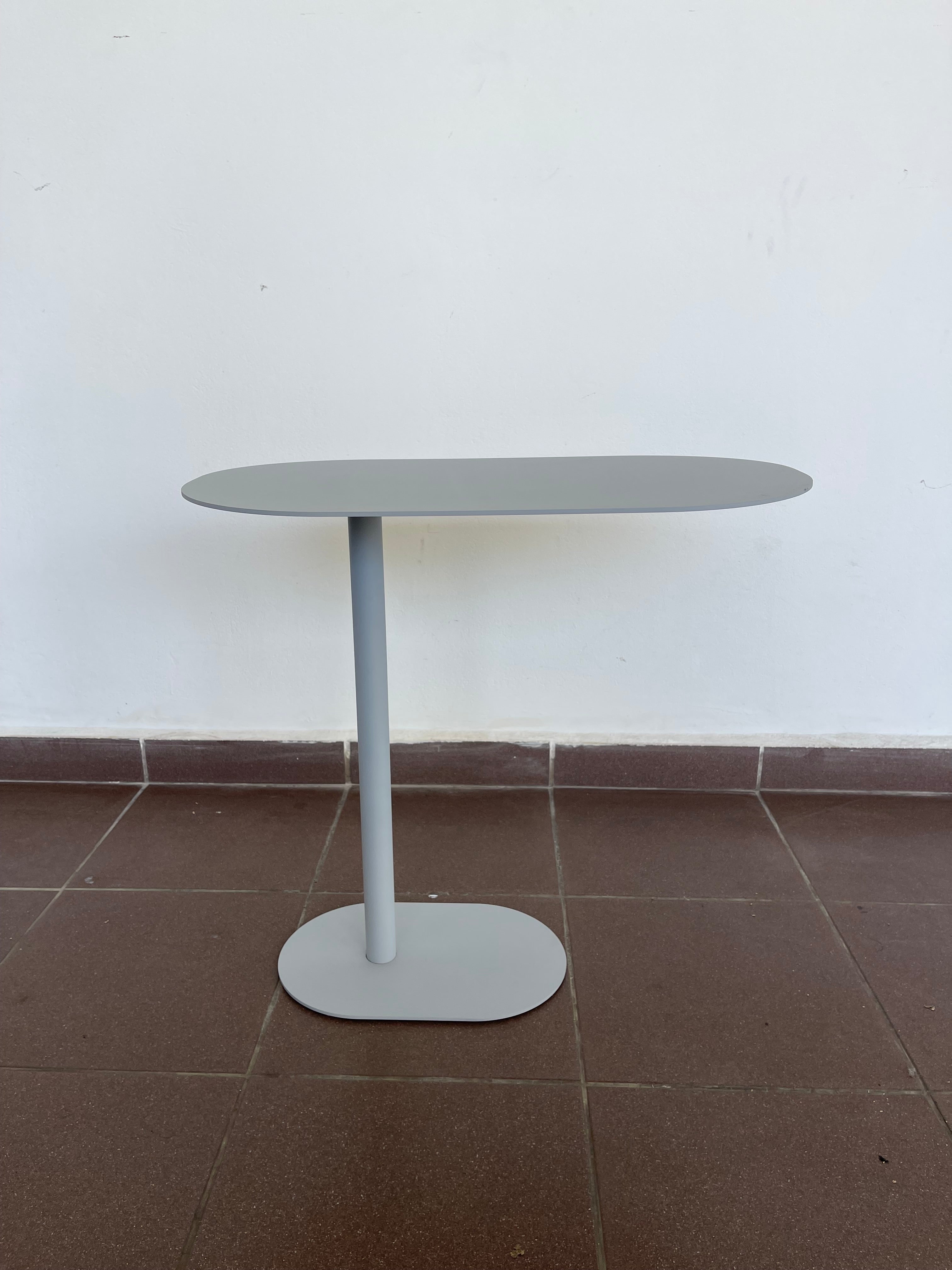 Contemporary black C-shaped side table with an oval top, positioned over a sofa.