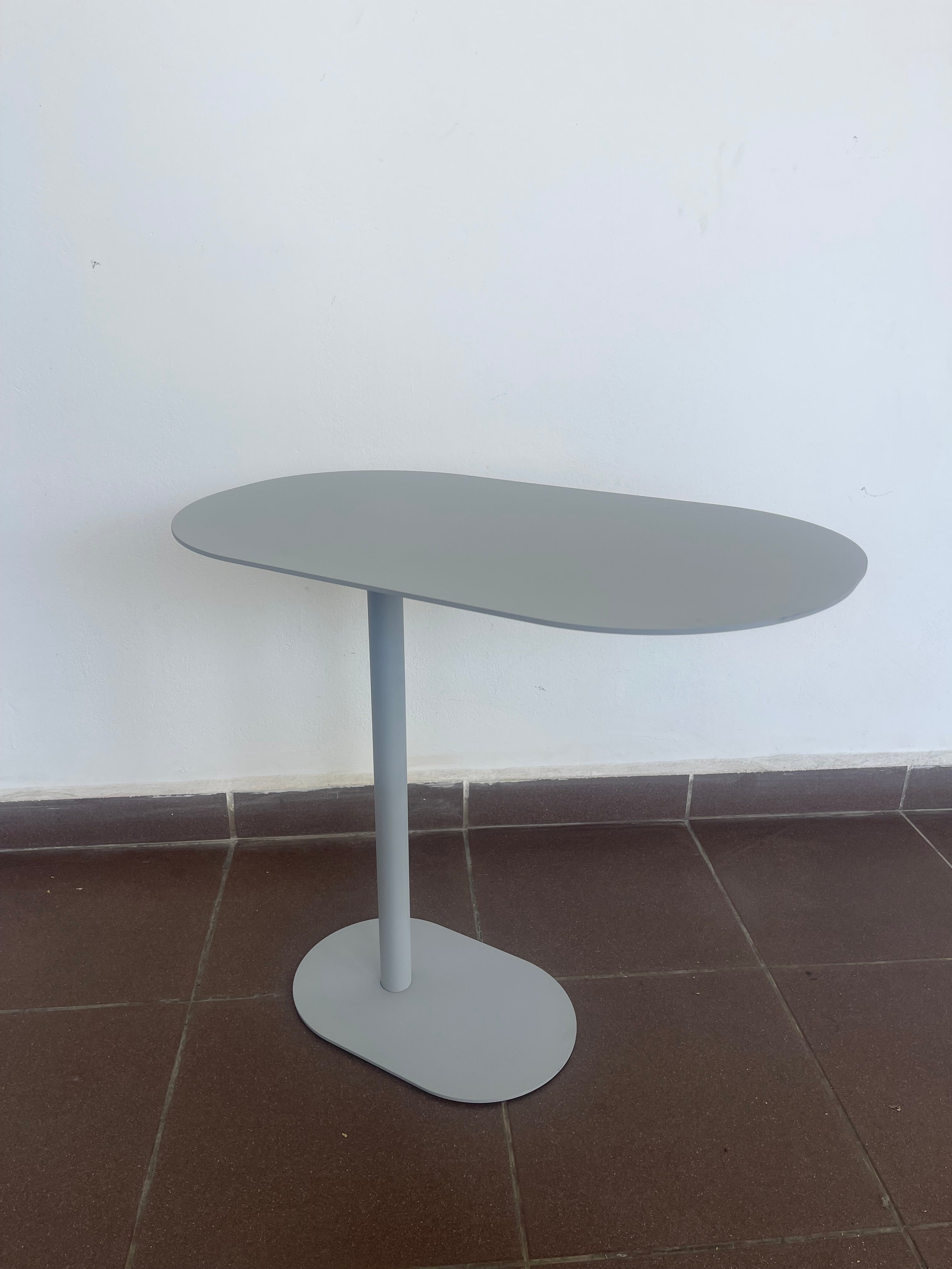 Contemporary black C-shaped side table with an oval top, positioned over a sofa.