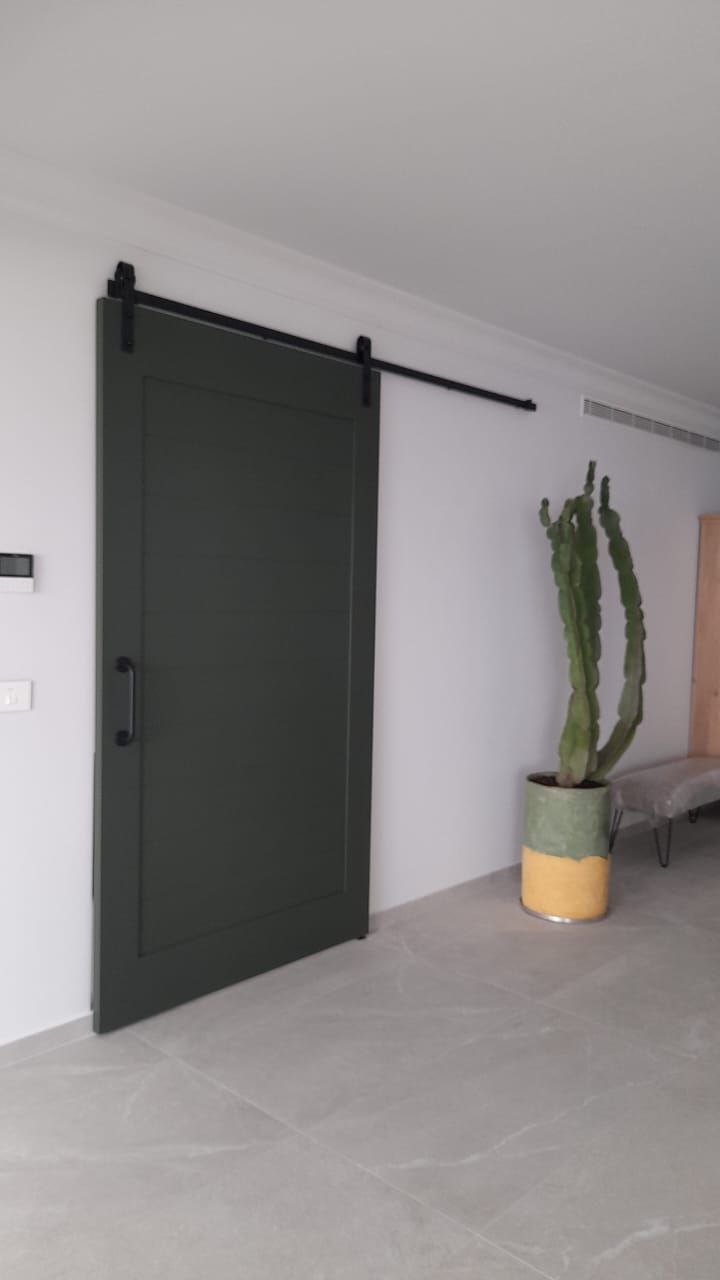 Modern dark-colored sliding door with horizontal grooves, featuring a black handle and track in a contemporary interior.
