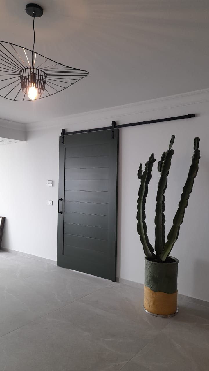 Modern dark-colored sliding door with horizontal grooves, featuring a black handle and track in a contemporary interior.