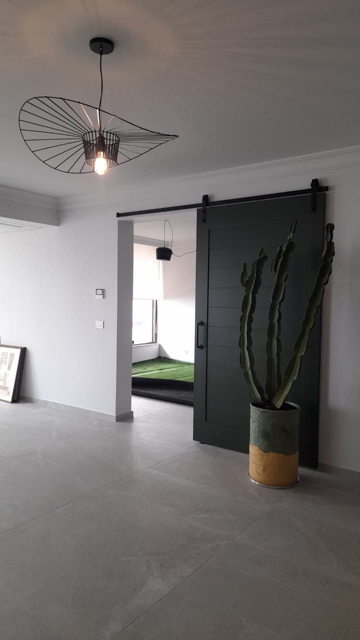 Modern dark-colored sliding door with horizontal grooves, featuring a black handle and track in a contemporary interior.