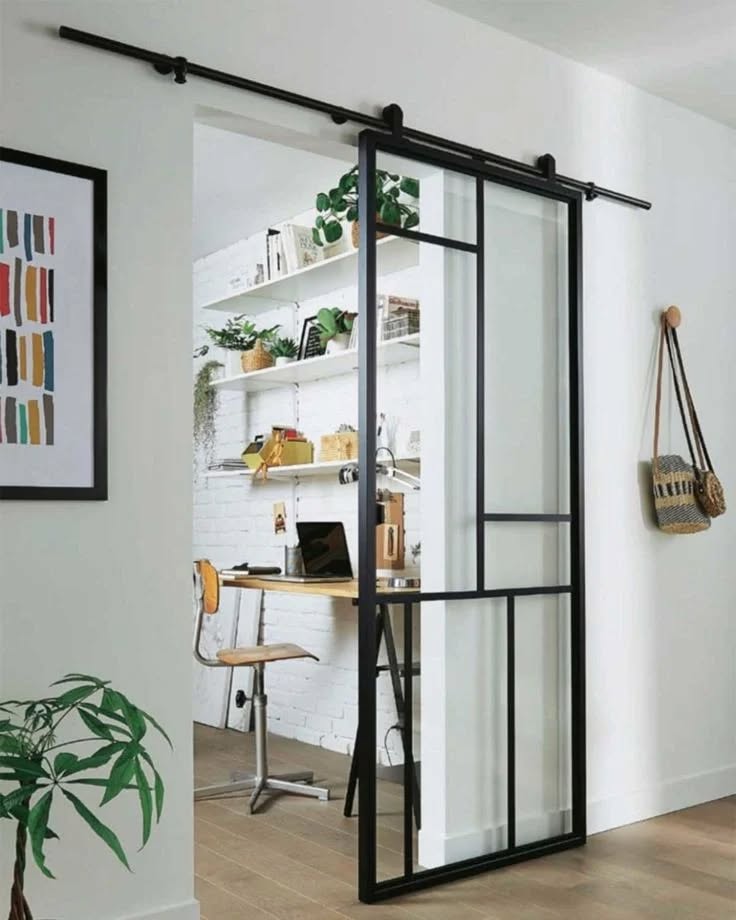 Modern glass sliding door with black metal framing and frosted panels, mounted on a black track