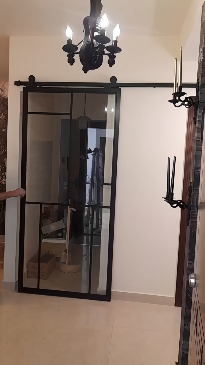 Modern glass sliding door with black metal framing and frosted panels, mounted on a black track