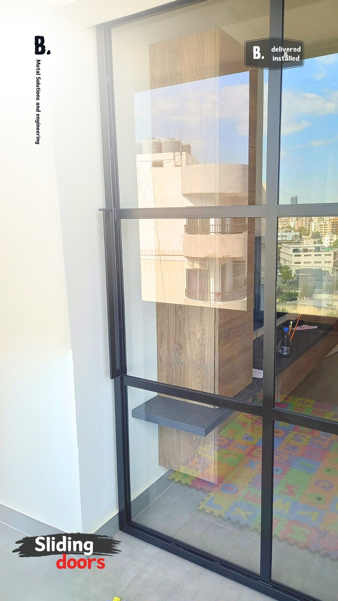 Modern glass sliding door with black metal framing and frosted panels, mounted on a black track