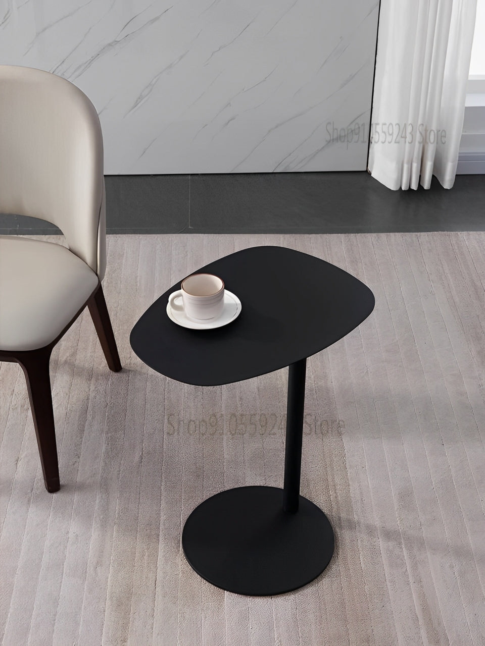 Modern black side table with a minimalist design, featuring a round base and an asymmetrical top.