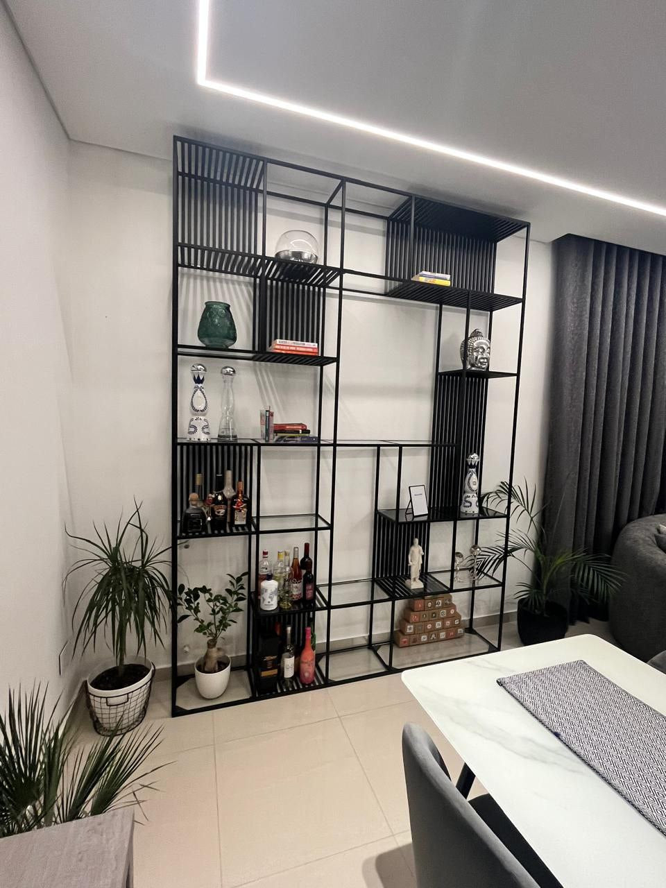 Grid Black Metal Modular Shelving Unit with multiple compartments, displaying books, vases, and decorative objects. Modern industrial shelving for home decor and storage in Lebanon.
