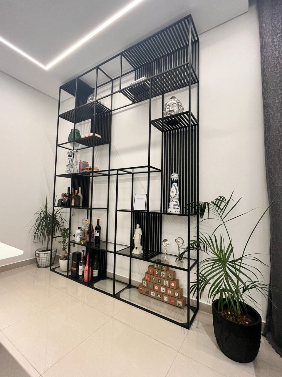 Grid Black Metal Modular Shelving Unit with multiple compartments, displaying books, vases, and decorative objects. Modern industrial shelving for home decor and storage in Lebanon.