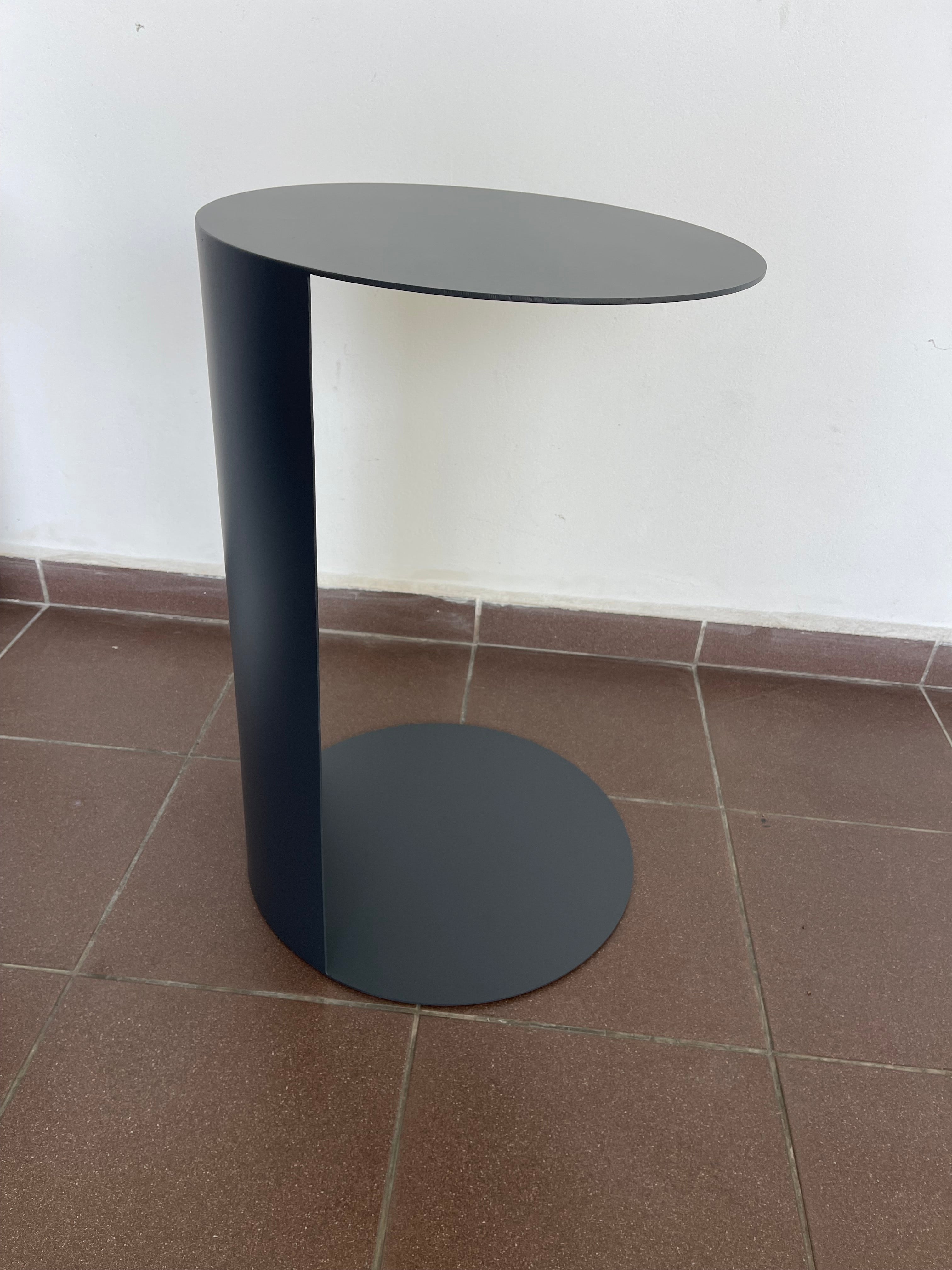 Minimalist dark grey C-shaped side table for sofa or chair.