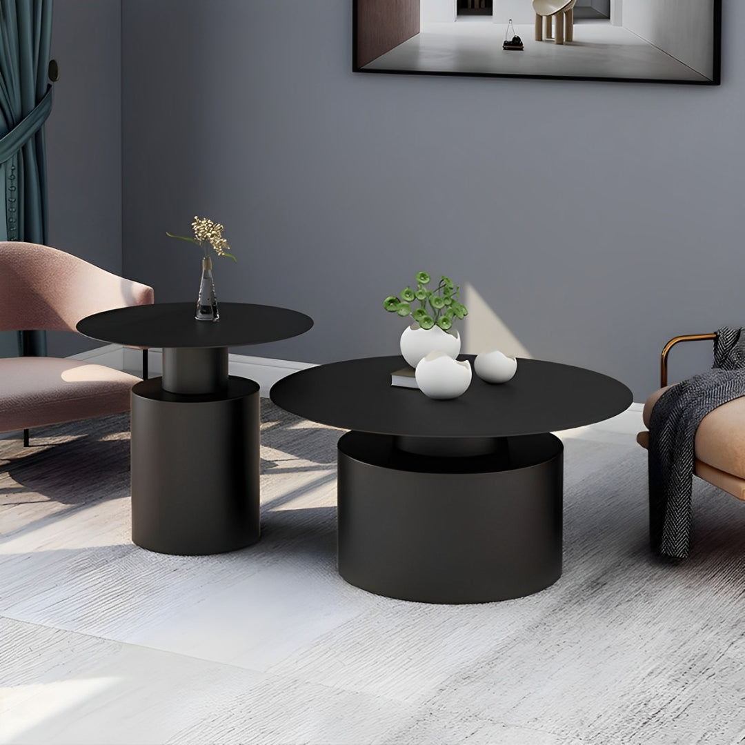 Modern nesting coffee tables with geometric shapes, featuring black metal oval and round tops and cylindrical bases.