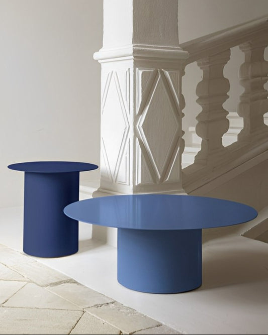Minimalist interior featuring a large and a small blue cylindrical-base round table.