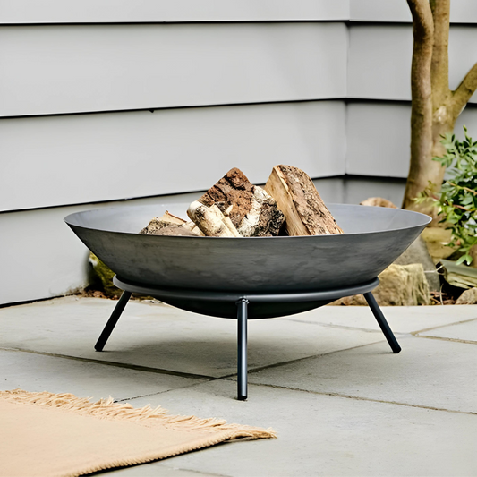 A metal fire pit bowl designed for outdoor use, filled with firewood and ready for burning.